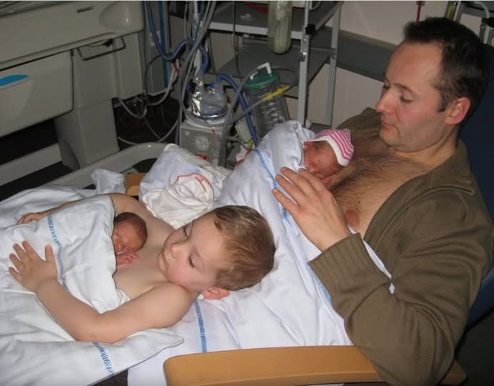 Young boy helps dad to keep his newborn twin siblings warm in viral photo